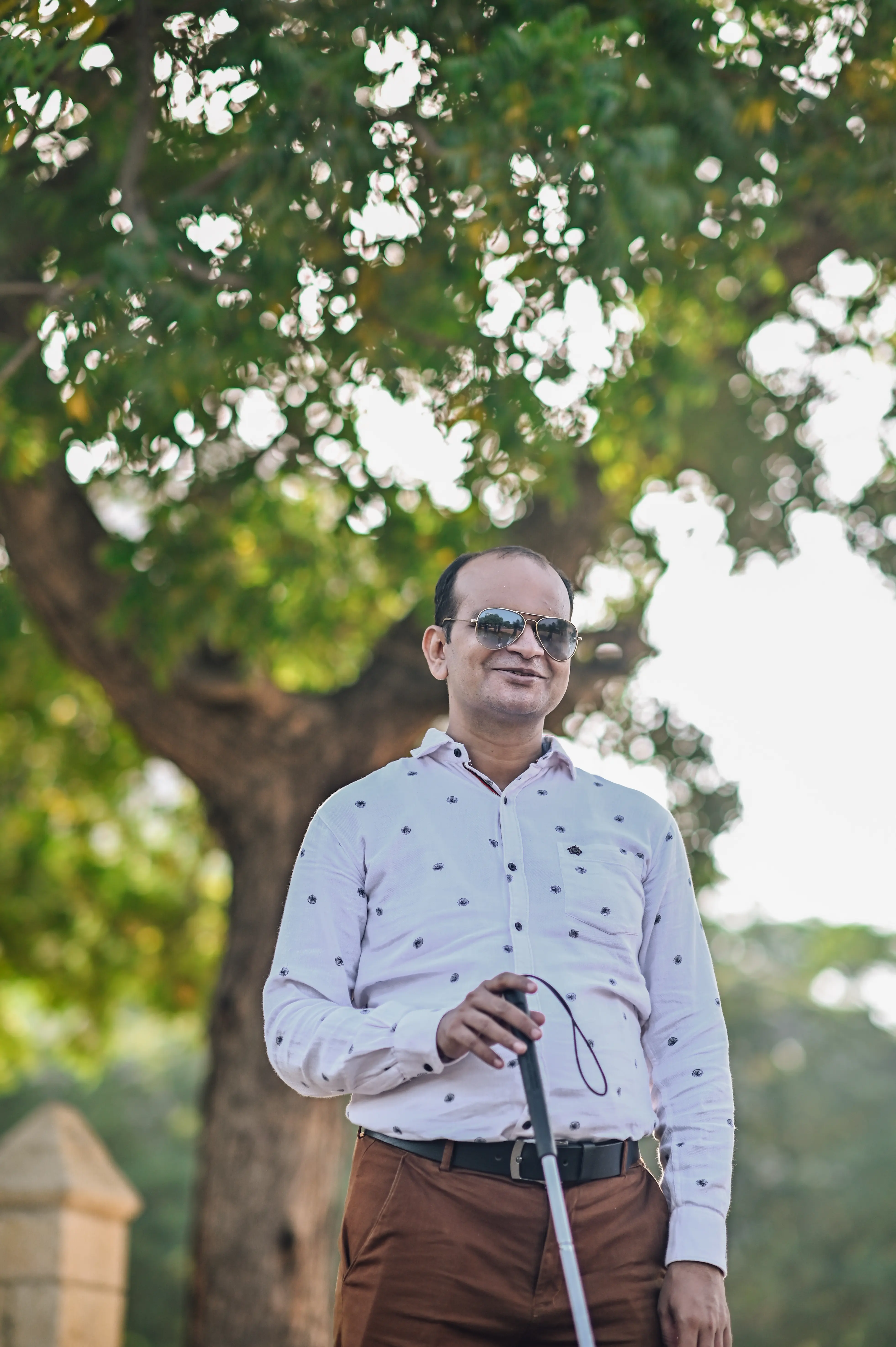 A man with a visual disability confidently holding his white cane outdoors